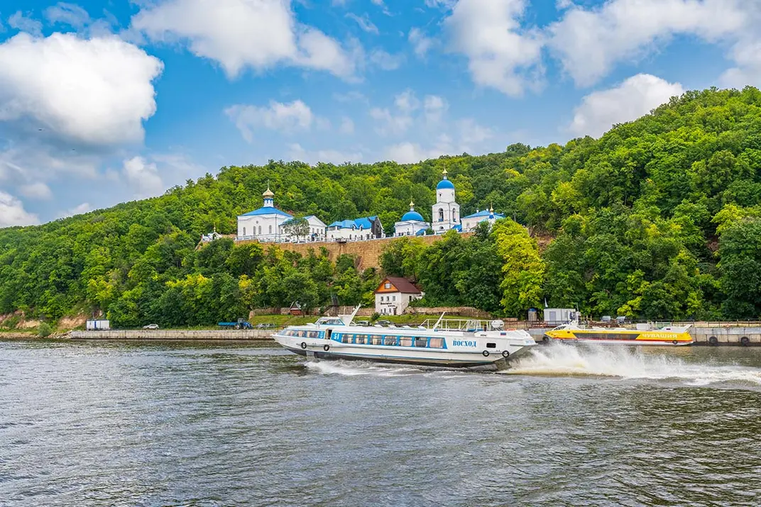 Теплоход идет по воде на фоне деревьев и Макаровского монастыря у Свияжска