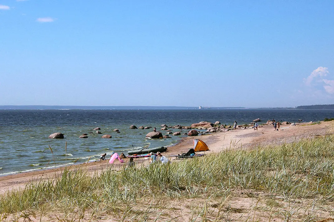 Женщина запускает воздушного змея на пляже у моря в солнечный летний день