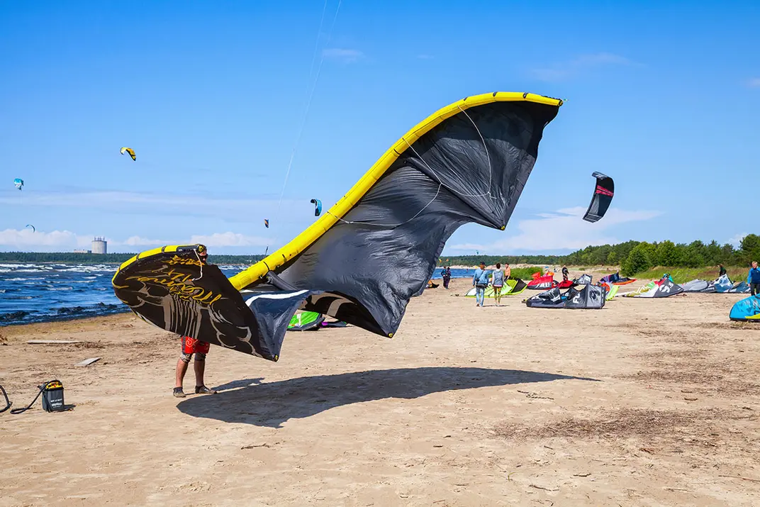 Кайтсерфер на пляже готовит спортивное снаряжение к катанию