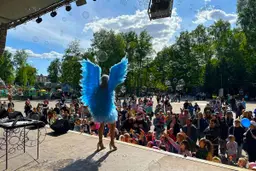 Девушка в голубом костюме ангела выступает на сцене в парке
